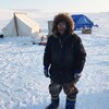 Personne en habit d'hiver sur une banquise et devant une tente, en 2018, à Ulukhaktok, aux Territoires du Nord-Ouest.
