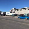 Édifice et rue au centre-ville de Yellowknife, avec voiture stationnée le long d'un terrain vacant.