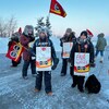 Des employés en hiver à l'extérieur avec des pancartes et des drapeaux à l'effigie du syndicat. Photo prise le 8 février 2023.
