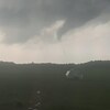 Une tornade se dessine dans le ciel d'une campagne. 