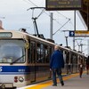 Un homme aux cheveux blancs attend de pouvoir entrer dans un train léger.
