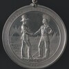 Une médaille sur laquelle sont gravés un chef autochtone et un officier britannique se serrant la main.
