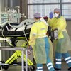 Une ambulancière fait un signe de la main pendant qu'elle pousse avec une collègue une civière dans un couloir de l'hôpital.