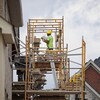 Un maçon installe des briques sur la façade d'une maison en construction.