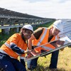 Un homme blanc et une femme aborigène travaillent sur un panneau solaire.
