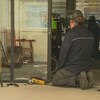 Un homme installe une caméra dans l'entrée d'un immeuble de logements à loyers modiques.