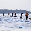 Des gens sur un lac qui traînent de l'équipement à ski. 