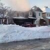 Une voiture devant une maison brûlée.