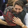 Le premier ministre Justin Trudeau est photographié alors qu'il enlace une femme migrante portant un foulard sur sa tête.