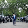 Donald Trump marche entre deux rangées de policiers.