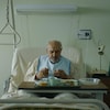 Un homme mange son repas dans un lit d'hôpital.
