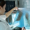 Une radiologue examine un film radiographique thoracique d'un patient dans un laboratoire.