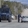 Un blindé de la police sur la route et des policiers qui interceptent des automobilistes.