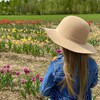 Une jeune fille est debout face à un champ de tulipes.