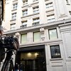 Un homme pointe sa grosse caméra devant la porte d'entrée de l'édifice du Twenty Air Street à Londres. 
