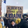 Une manifestante tient une affiche qui dit que l'Alberta soutient l'Ukraine.
