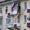 Un homme agite un drapeau russe à la fenêtre d'un immeuble.