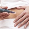Une femme s'apprête à s'injecter une dose d'insuline dans l'abdomen.