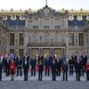 Des chefs d'État sont debout devant le château de Versailles, en France.