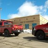 Deux camionnettes rouges des pompiers de Moncton sont immobilisées devant un bâtiment de brique jaune sur lequel les mots « Sciences de l'environnement » sont écrits.