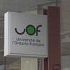Affiche près d'un immeuble sur lequel on peut lire UOF, Université de l'Ontario français.