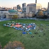 Plusieurs dizaines de tentes sont installées sur une grande pelouse dans uen ville. 