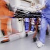 Photo d'infirmiers en mouvement poussant une civière dans un couloir.