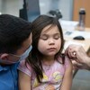 Une fillette accompagnée de son père se fait vacciner. 