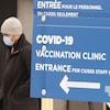 Un homme masqué passe près d'une pancarte annonçant la clinique. 