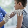 Un garçon d'environ 7 ans se fait vacciner par une infirmière.