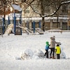 Deux enfants et un adulte font un bonhomme de neige dans un parc de Vancouver le 30 novembre 2022.