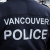 Un homme de dos porte un chandail sur lequel il est écrit Vancouver Police