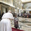 Le pape serre la main à une femme inuit devant une salle pleine