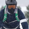 Un cycliste en plein hiver portant un casque et des lunettes de ski. 