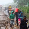 Une file de personnes marchent sous la pluie.