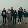Huit élèves sur un pont en extérieur en chantant le coeur sur la main.