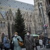Des personnes masquées marchent devant la cathédrale Saint-Étienne, à Vienne.