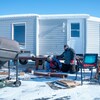Deux personnes installent une cabane sur la glace.