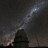 On voit le ciel étoilé et un observatoire au sol.