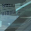Un carton sur lequel est inscrit Vendu accroché au rétroviseur intérieur d'une voiture.