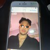Photo d'un téléphone cellulaire qui affiche l'image d'un homme qui porte des lunettes de soleil aux bords orange.