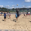 Deux équipes de volleyball de plage s'affrontent sur un terrain dans le sable. 