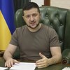 Volodymyr Zelensky, portant un t-shirt kaki, assis dans un fauteuil vert derrière son bureau. 