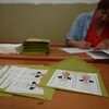 Une femme écrit sur un papier près de bulletins de vote à l'image des candidats à la présidence turque.