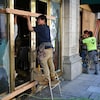 Des ouvriers réparent la devanture d’un restaurant.