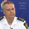 Un policier devant un fond bleu de la police de Brandon.