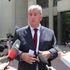 Glen Murray, candidat à la mairie de Winnipeg, prend la parole à l'extérieur de l'hôtel de ville en juin 2022 au micro de plusieurs journalistes. Il a les cheveux blancs et porte un veston noir et une cravate bourgogne.