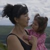 Diane Abel tient dans les bras sa petite fille en regardant le paysage du futur barrage.