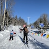 Une femme et quatre enfants commencent leur promenade sur une piste de ski de fond.
