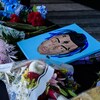 Des fleurs et une illustration représentant le rappeur décédé XXXTentacion ont été déposées sur un trottoir.   